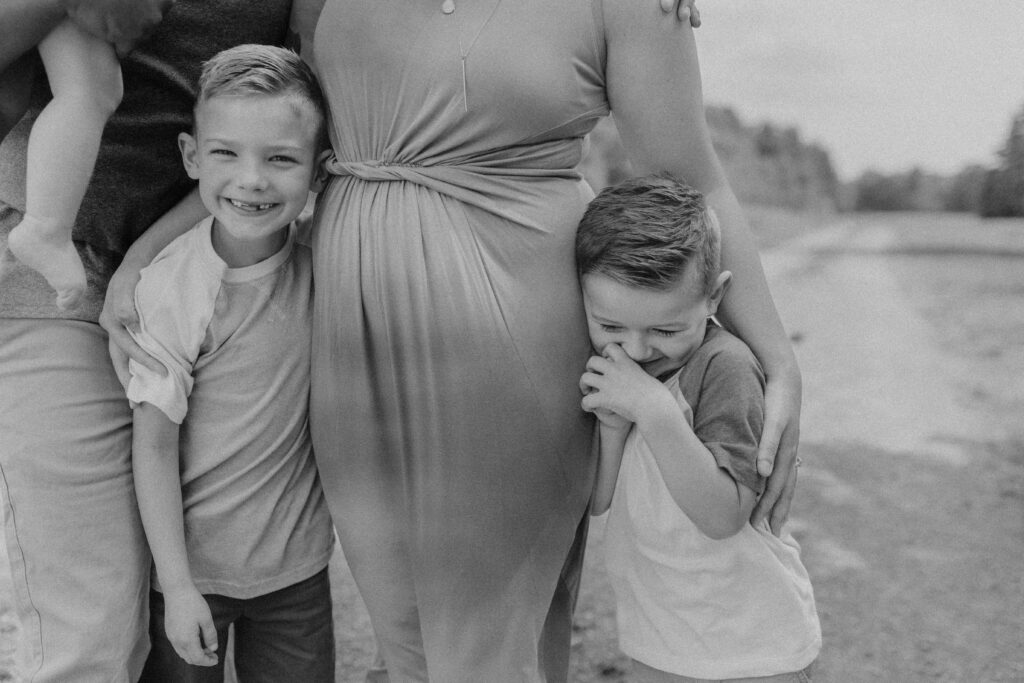 2 boys giggle while moms arms are around them