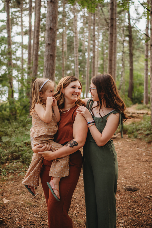 mom and daughters laughing in the woods
