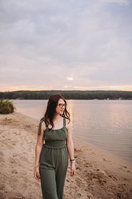 teenager walks by water at sunset